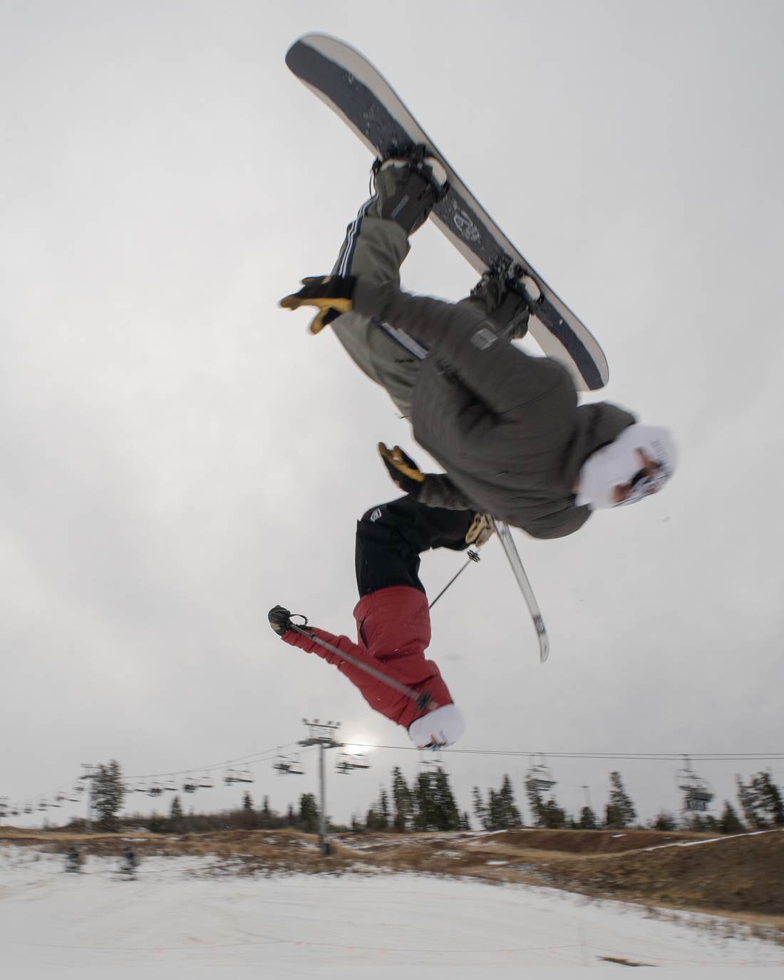 Two riders in Make Homies ski masks, upside down mid-flip over a ski hill
